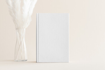 White book mockup with a pampas decoration on the soft yellow background.