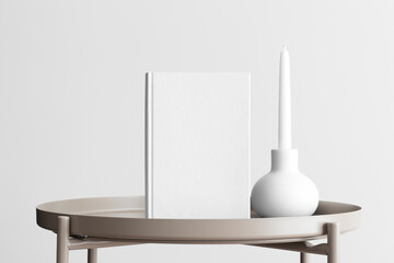 White book mockup with a candle decoration on the beige table.
