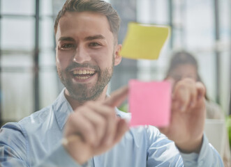 businessman is working on a project. Business man pointing at a note on the glass wall in the office.