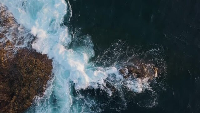 Overhead view of waves splash on rocks