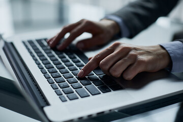 Close-up of male hands using laptop at office
