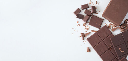 Pieces of dark chocolate isolated on white background. Flat lay, top view with copy space.