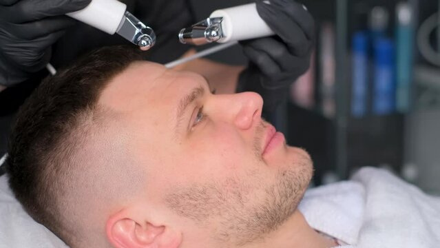 A female cosmetologist performs a cavitation procedure. Rejuvenation of facial skin for men
