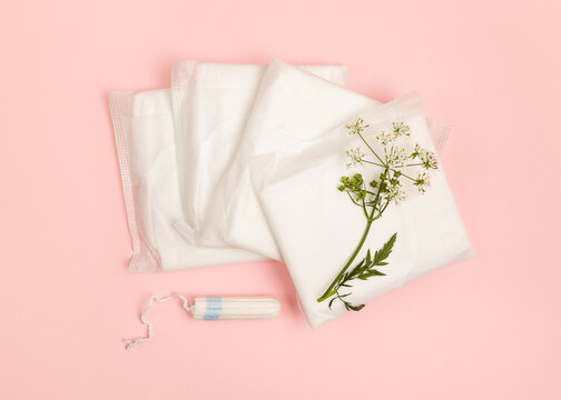 Sanitary pads and tampon on a pink background.