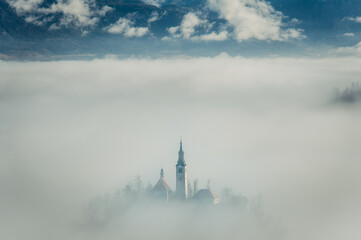 A mesmerizing scene of Bled Lake enveloped in ethereal mist, with only the church standing out...
