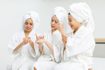 Millennial three Asian female customers friends in white clean bathrobes and towels have...