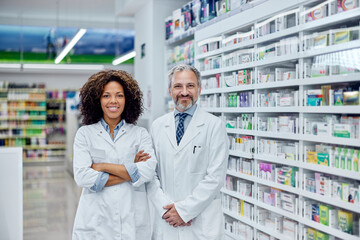 Portrait of two colleagues, working at the pharmacy, dressed in a white uniform.