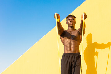 Young man doing stretching exercise outside. African man training at the beach.