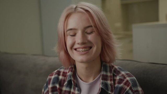 20s Woman with Dental Braces Laughing at Camera. Cheerful pink hair female smiling looking at camera. Close up, zoom in.