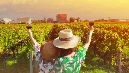 Happy time with back view of young women friends drinking red wine,which happy moment in vineyard in summer