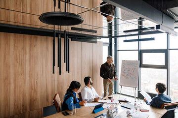 Professional serious multinational team discuss marketing strategy in office