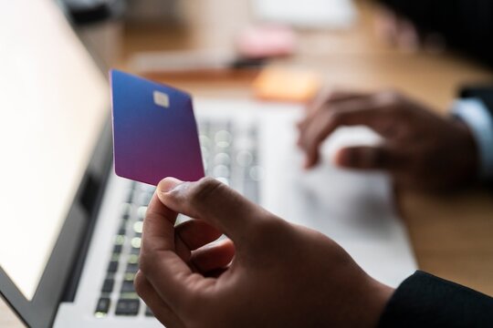 Unrecognizable male using modern laptop while entering credit card credentials into computer during online shopping