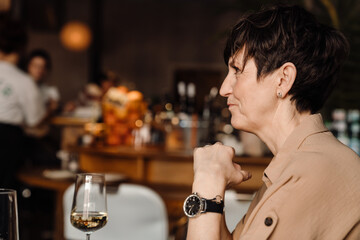 Happy mature woman sitting with glass of wine in cafe
