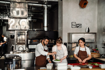 Three multinational chefs prepare healthy food in kitchen