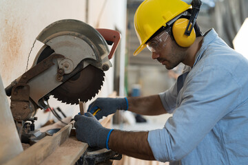 Male carpenter using electrical circular saw electric during working in wood workshop. Male joiner...