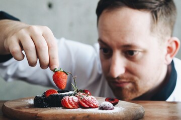 Close up master chef hands making a delicious strawberry tart in the kitchen bakery.
