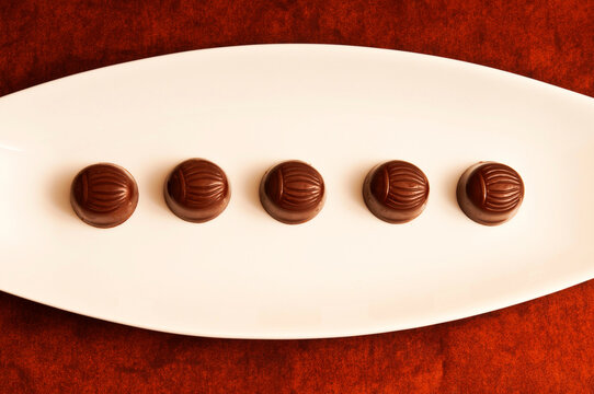 chocolate bonbons or pralines  on a white porcelain plate in a row like graphic food background 