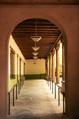 Hallway with lamps and an arch in an adobe building