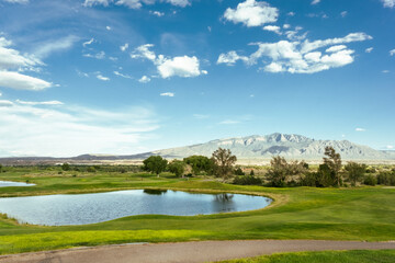 Sierra de Sandía Mountains in front of a field and a lake in New Mexico