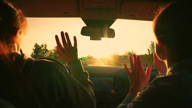 Female students driving in car listening to musical song on way sing and dance. Two happy women in car listening to radio, driving towards sun. Concept of youth, friendship, vacation travel at sunset