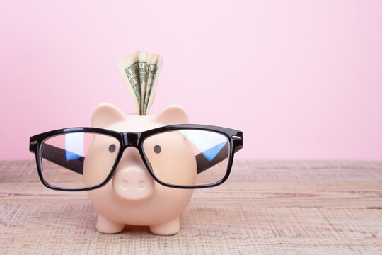 Piggy bank wearing a black glasses over pink background. Financial specialist.