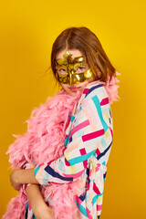 A joyful teenager girl wearing a colorful Brazil carnival mask
