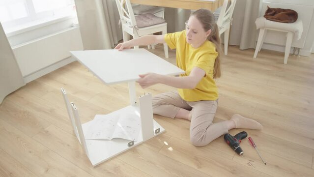 Woman self assembly of furniture at new home sitting on floor