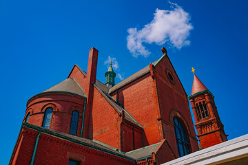 Red brick church in Beverly, Massachusetts, close-up with a white cloud in the blue sky