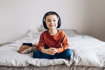 Happy smiling child enjoys listen to the music in headphones at home