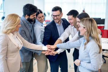 Fototapeta na wymiar Group of businesspeople stacking hands in a tight circle, to strategize, motivate or celebrate their unity in the office.