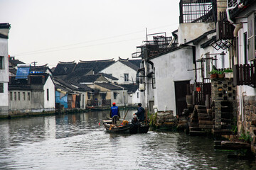 Fototapeta na wymiar boat with two people travelling down a canal in suzhou