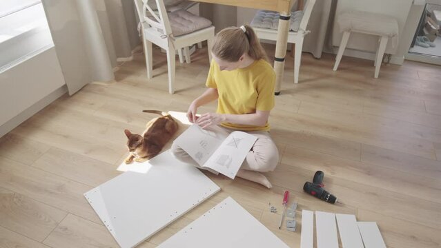 Woman reading manuals to assembling furniture at home