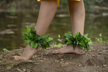 Close up detail of a woman's bare feet on the ground wearing hula dancer anklets.