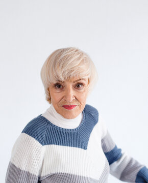 Studio portrait of an older woman. An older model with short gray hair. Fashion photography in the studio. Self-confident portrait of an older woman.