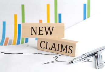 NEW CLAIMS text on a wooden block on chart background , business concept