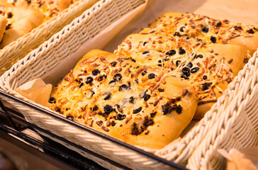 rectangular pizza with cheese and olives on a bakery counter