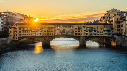 Fotobehang Ponte Vecchio A rising sun above the Ponte Vecchio in Florence early in the morning.