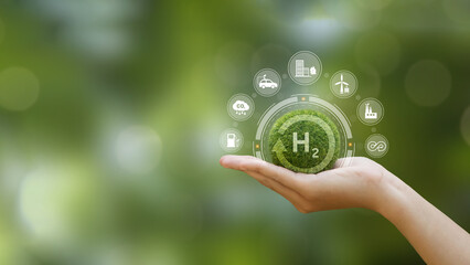 Hand of human holding green earth with the icon of H2 for Clean hydrogen energy...
