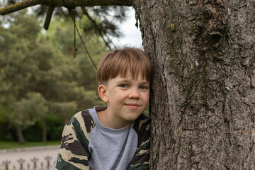 Cute boy by the tree. he is currently looking at the camera and smiling