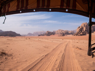 View of tire tracks in the sand of the Wadi Rum desert from the back of a Jeep.