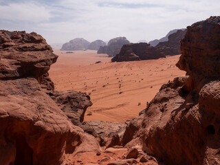 Wadi Rum desert visible through a limestone rock formation, vast open area of sand. 