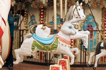 Children's vintage carousel with figures of a hare and a horse. A working carousel without people. Colorful fair carousel on the square.