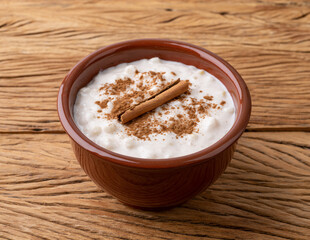 Canjica or munguza, typical brazilian white corn sweet cream with cinnamon over wooden table