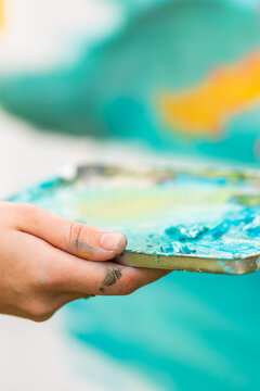 Artist holding messy paint pallet tray for mixing colours