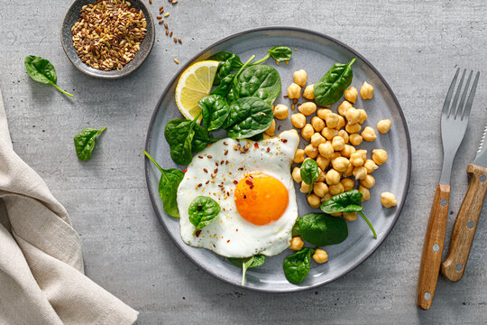 Egg fried, boiled chickpea and fresh spinach for healthy breakfast, top view