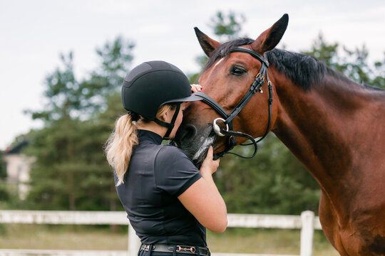 Young female horsewoman petting and bonding with her horse outside in nature