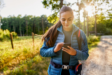 Woman using smartphone during trekking adventure in forest