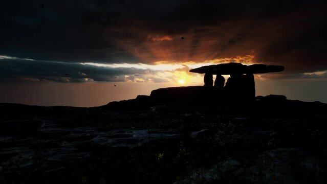 The sun rising behind the silhouette of the Poulnabrone Dolmen in the Burren, County Clare, Ireland. 