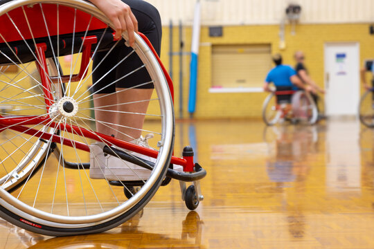 wheel of wheelchair dominating foreground with wheelchair basketball players blurred in background