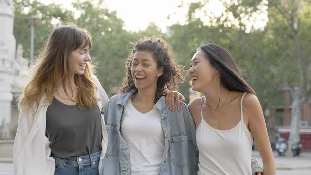 Three young multicultural women having fun on city street outdoors - Mixed race female friends enjoying  summertime vacation together - Friendship concept with happy girls laughing out loud 